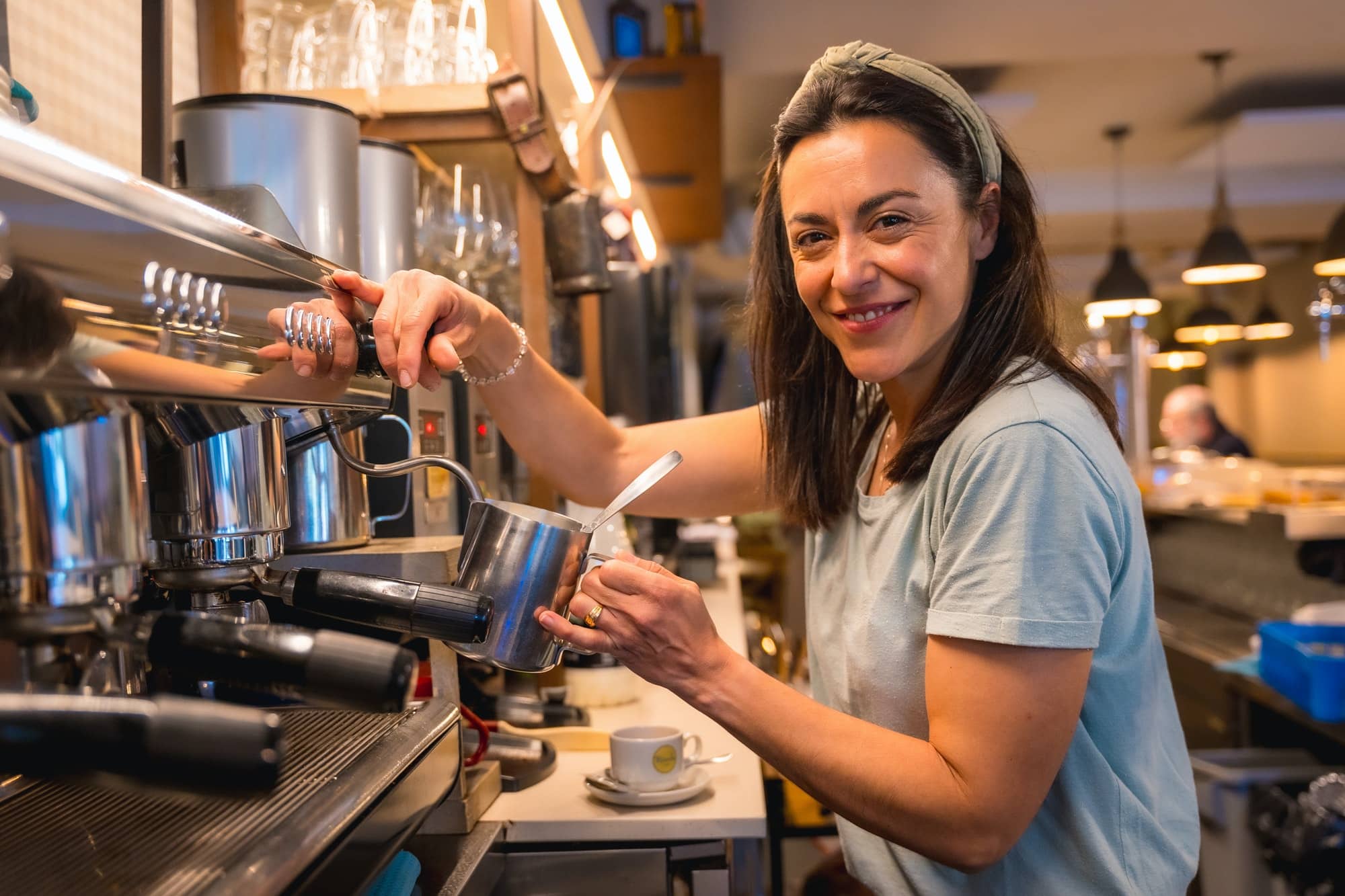 Female cafe owner preparing coffee in a coffee machine, preparing a latte
